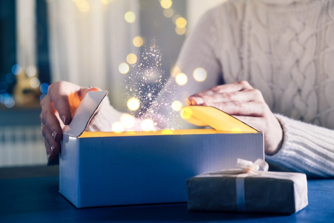 Person opens gift, miracles and wishes come true on Christmas eve. Close-up of hands and New Year pr